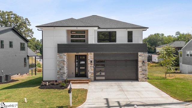 view of front facade featuring a garage, central AC unit, and a front yard