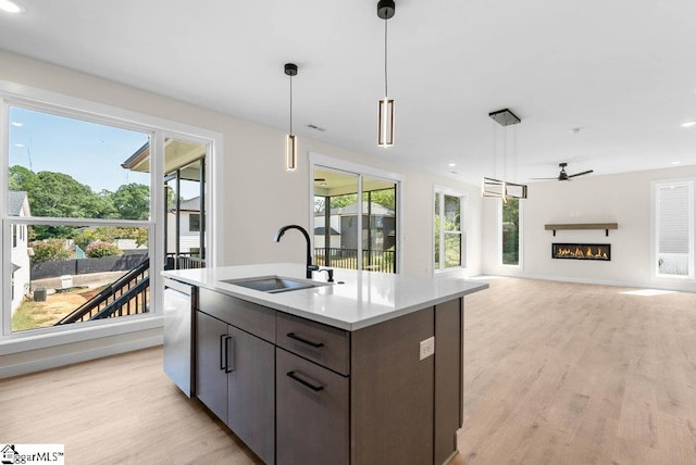 kitchen featuring an island with sink, stainless steel dishwasher, hanging light fixtures, and sink