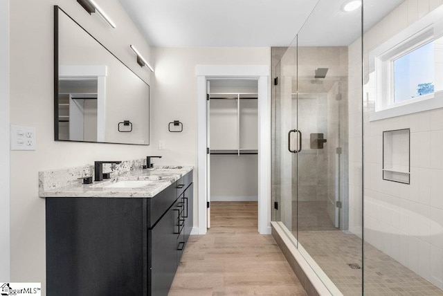 bathroom featuring a shower with shower door, hardwood / wood-style flooring, and vanity