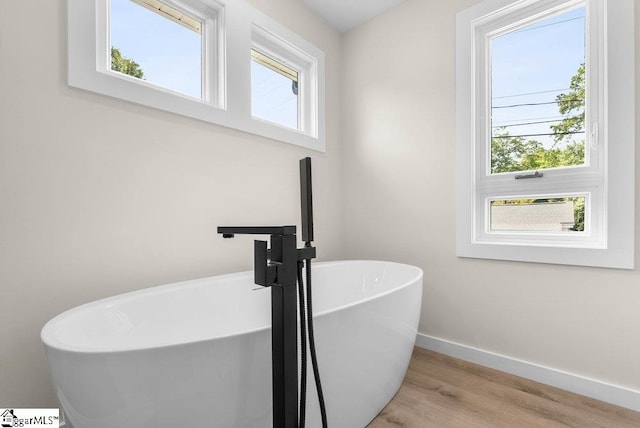 bathroom with plenty of natural light, hardwood / wood-style floors, and a bathing tub