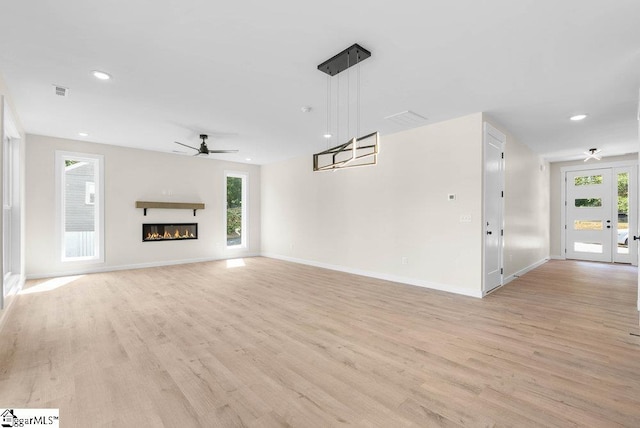 unfurnished living room featuring ceiling fan, light hardwood / wood-style flooring, and a healthy amount of sunlight