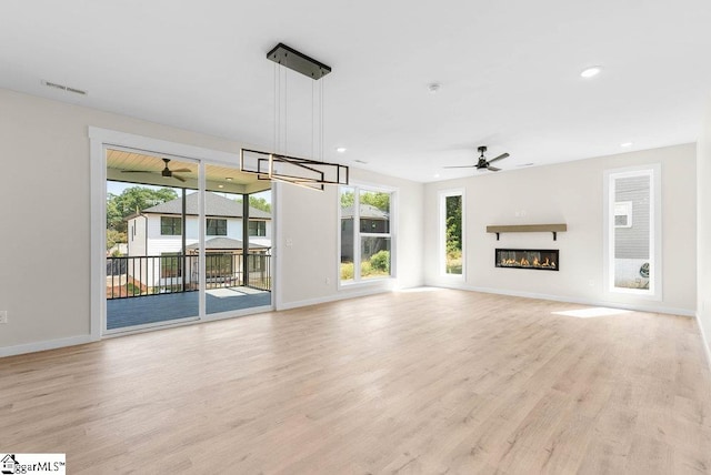 unfurnished living room with light wood-type flooring, ceiling fan, and a wealth of natural light