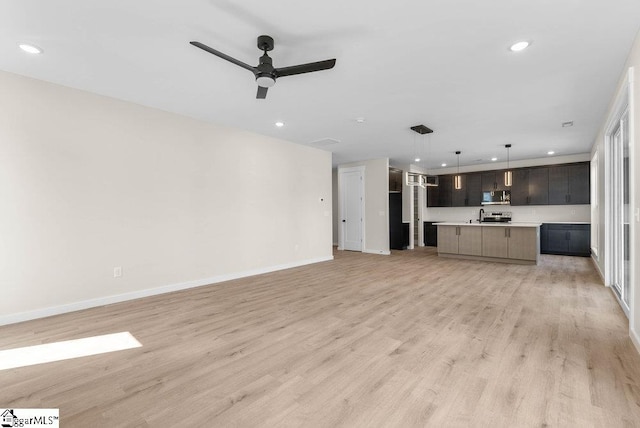 unfurnished living room featuring light wood-type flooring, sink, and ceiling fan