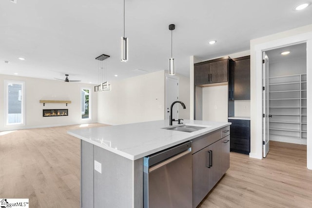 kitchen featuring light hardwood / wood-style floors, stainless steel dishwasher, a kitchen island with sink, and sink