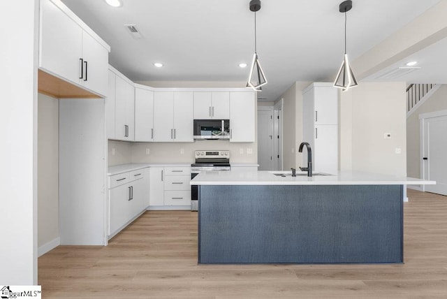 kitchen featuring an island with sink, white cabinets, stainless steel appliances, light hardwood / wood-style flooring, and decorative light fixtures