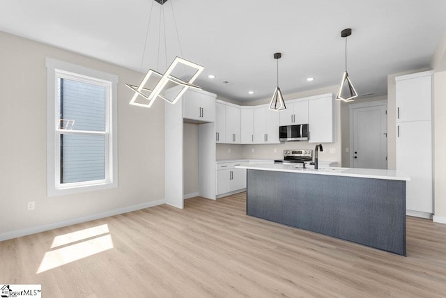 kitchen with white cabinets, a kitchen island with sink, appliances with stainless steel finishes, and light hardwood / wood-style floors