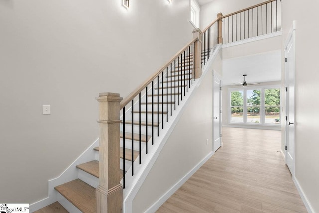 stairs with wood-type flooring and a towering ceiling