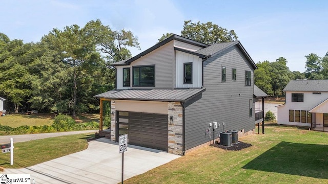 view of front of property with cooling unit, a garage, and a front yard