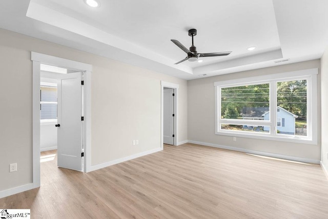 unfurnished bedroom with a tray ceiling, ceiling fan, and light hardwood / wood-style flooring