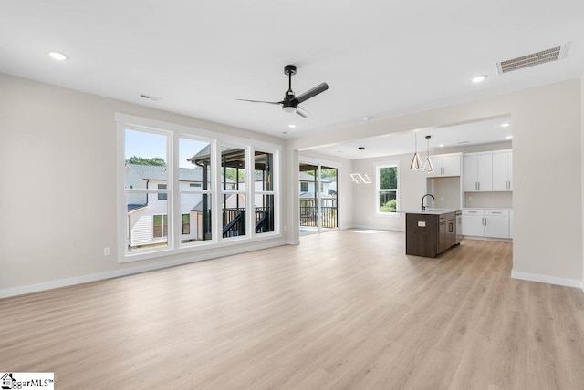 unfurnished living room featuring light wood-type flooring, ceiling fan, and sink