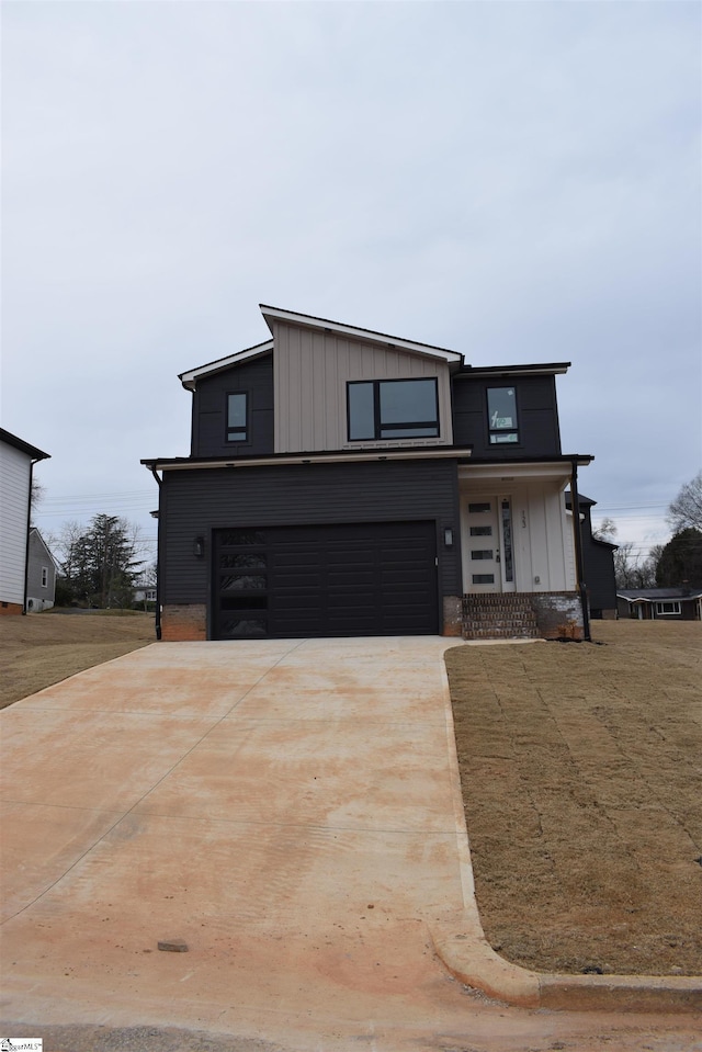 view of front facade featuring a garage, driveway, board and batten siding, and a front yard