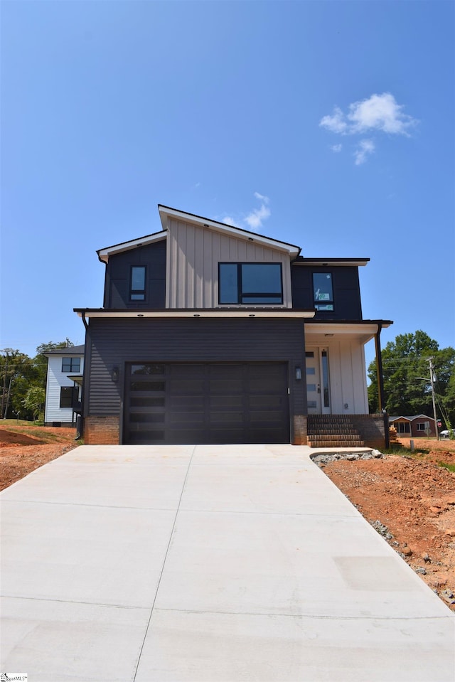 contemporary home with board and batten siding, concrete driveway, covered porch, and a garage