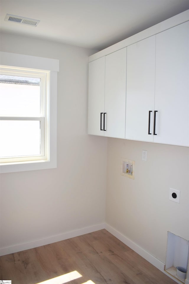 clothes washing area with washer hookup, cabinets, hardwood / wood-style floors, and electric dryer hookup