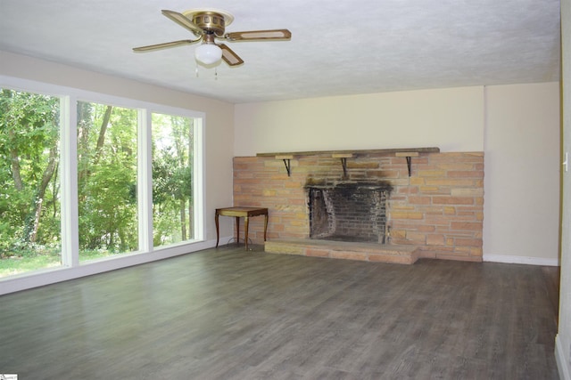 unfurnished living room with ceiling fan, a fireplace, dark wood-type flooring, and a wealth of natural light