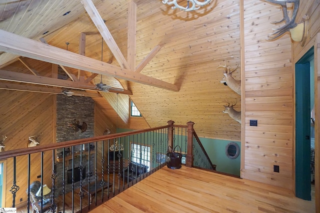 interior space with beamed ceiling, hardwood / wood-style flooring, wooden walls, and high vaulted ceiling