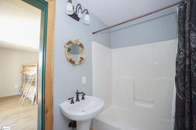 bathroom with hardwood / wood-style floors, shower / bath combo with shower curtain, and sink