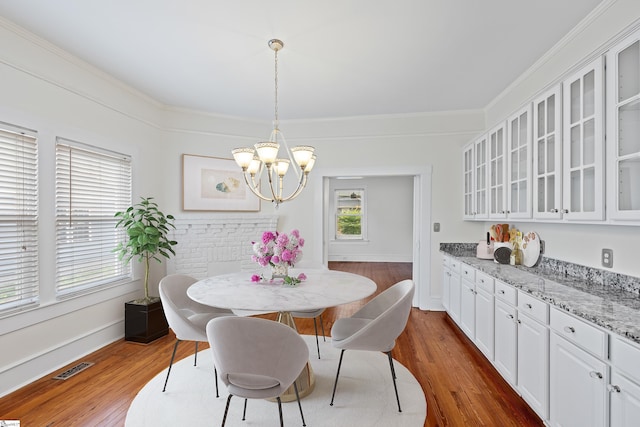 dining space with a notable chandelier, crown molding, and dark hardwood / wood-style flooring