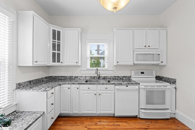 kitchen with white cabinets, light hardwood / wood-style flooring, plenty of natural light, and white appliances