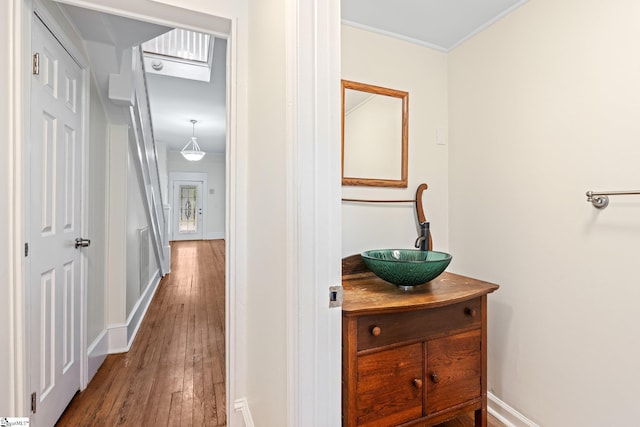 hallway with ornamental molding, wood-type flooring, and sink