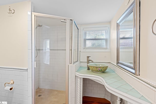 bathroom featuring tile walls, a shower with shower door, and vanity