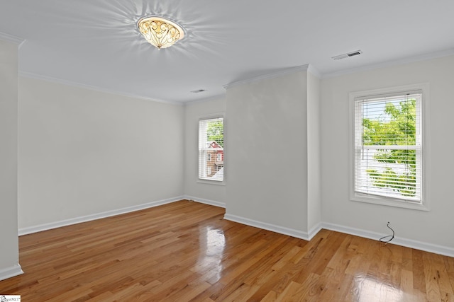 unfurnished room with light wood-type flooring, crown molding, and plenty of natural light