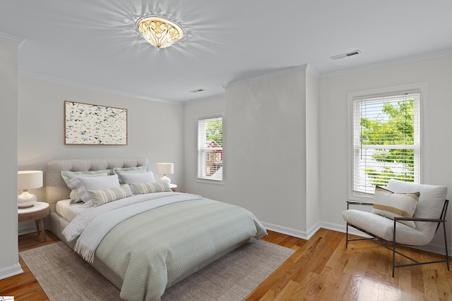 bedroom with light hardwood / wood-style flooring, multiple windows, and ornamental molding