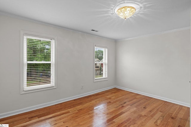 empty room featuring light wood-type flooring and ornamental molding