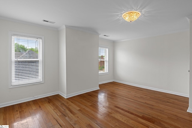 empty room with ornamental molding, hardwood / wood-style floors, and plenty of natural light