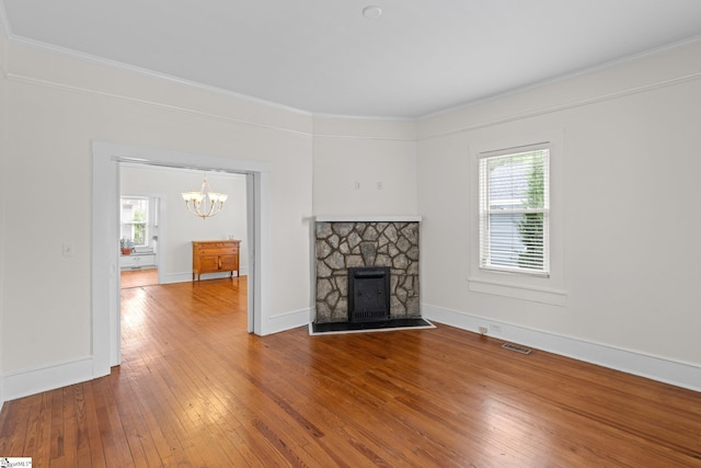 unfurnished living room featuring hardwood / wood-style floors, a fireplace, a healthy amount of sunlight, and crown molding