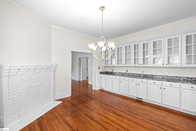 interior space with pendant lighting, a chandelier, dark hardwood / wood-style floors, white cabinetry, and crown molding