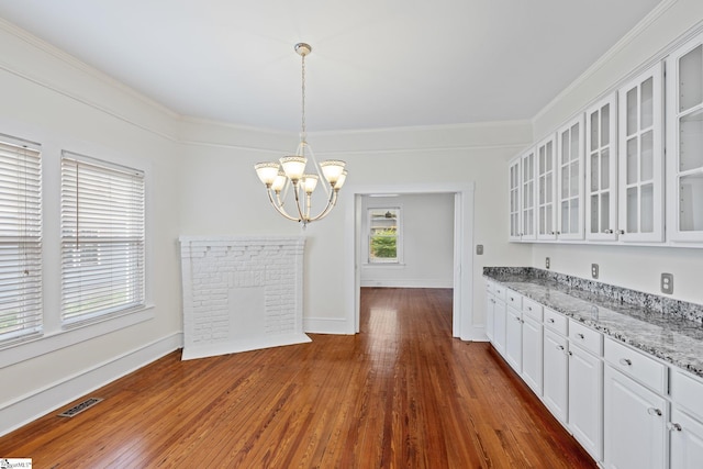 kitchen featuring white cabinets, an inviting chandelier, dark hardwood / wood-style flooring, ornamental molding, and light stone countertops