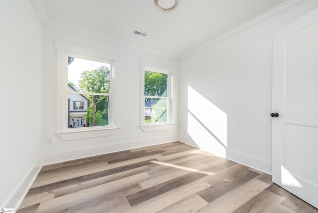 empty room with light wood-type flooring and crown molding