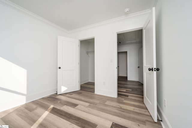 unfurnished bedroom with crown molding, a closet, and hardwood / wood-style flooring