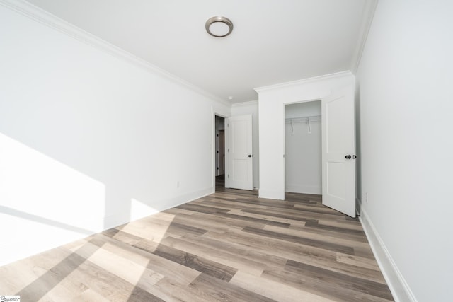 unfurnished bedroom with ornamental molding, a closet, and hardwood / wood-style floors