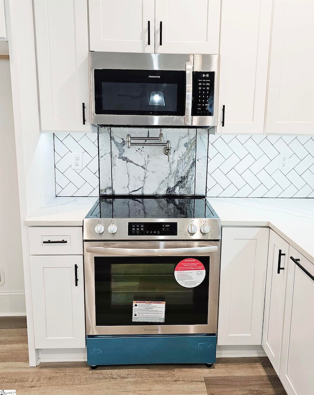 kitchen featuring light hardwood / wood-style flooring, stainless steel appliances, white cabinetry, and tasteful backsplash