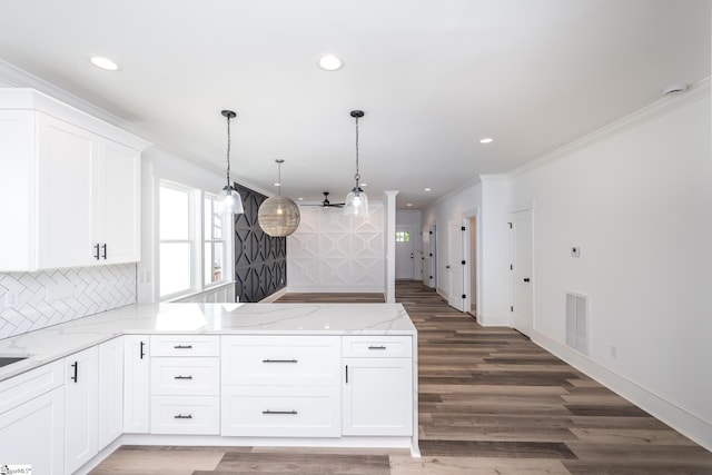 kitchen featuring hanging light fixtures, white cabinetry, dark wood-type flooring, light stone counters, and ornamental molding