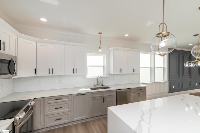 kitchen with pendant lighting, light stone counters, sink, white cabinets, and stainless steel appliances