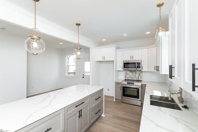 kitchen featuring ornamental molding, white cabinetry, hanging light fixtures, appliances with stainless steel finishes, and light stone countertops