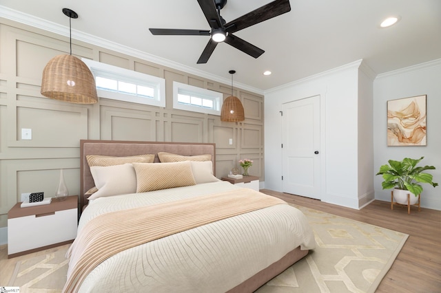 bedroom with ornamental molding, light wood-style floors, a decorative wall, and recessed lighting