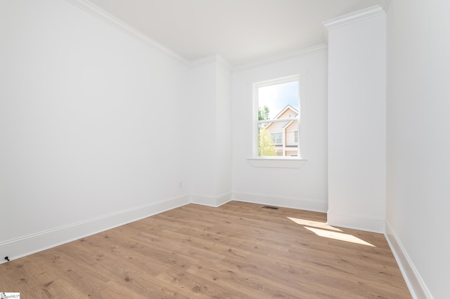 empty room with light wood-style floors, baseboards, and ornamental molding