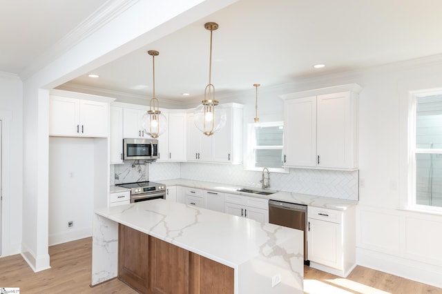 kitchen with white cabinetry, decorative light fixtures, appliances with stainless steel finishes, and a kitchen island