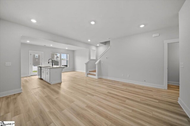 unfurnished living room featuring light wood-type flooring and sink