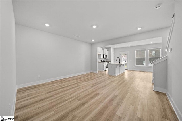 unfurnished living room with sink and light hardwood / wood-style flooring