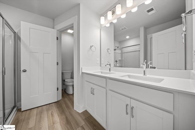 bathroom with vanity, hardwood / wood-style floors, an enclosed shower, and toilet