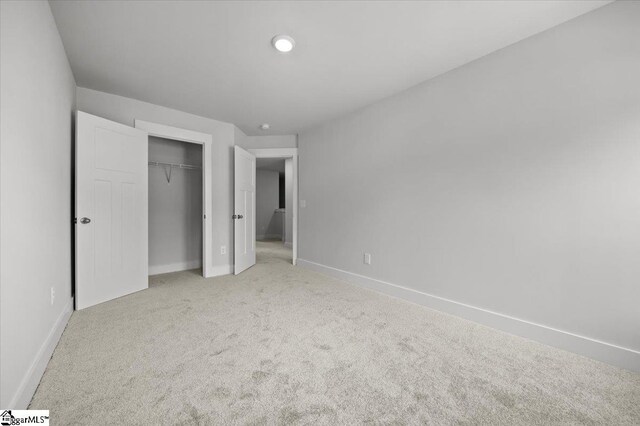 unfurnished bedroom featuring light carpet and a closet