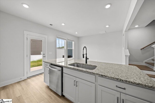 kitchen with light hardwood / wood-style floors, sink, white cabinetry, light stone countertops, and stainless steel dishwasher