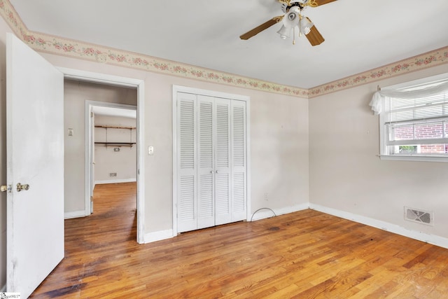 unfurnished bedroom with ceiling fan, a closet, and hardwood / wood-style floors