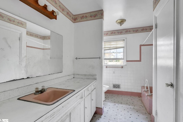 bathroom with tile patterned flooring, a shower, toilet, tile walls, and vanity