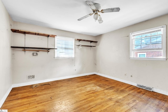 empty room with ceiling fan, hardwood / wood-style flooring, and plenty of natural light