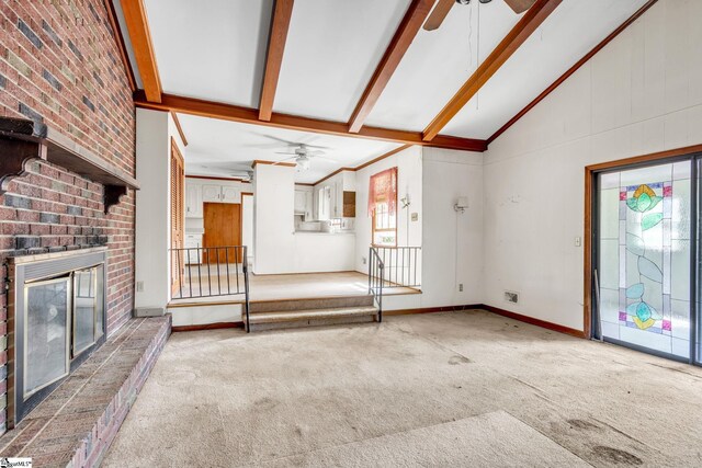 unfurnished living room with carpet floors, a brick fireplace, beamed ceiling, ceiling fan, and high vaulted ceiling